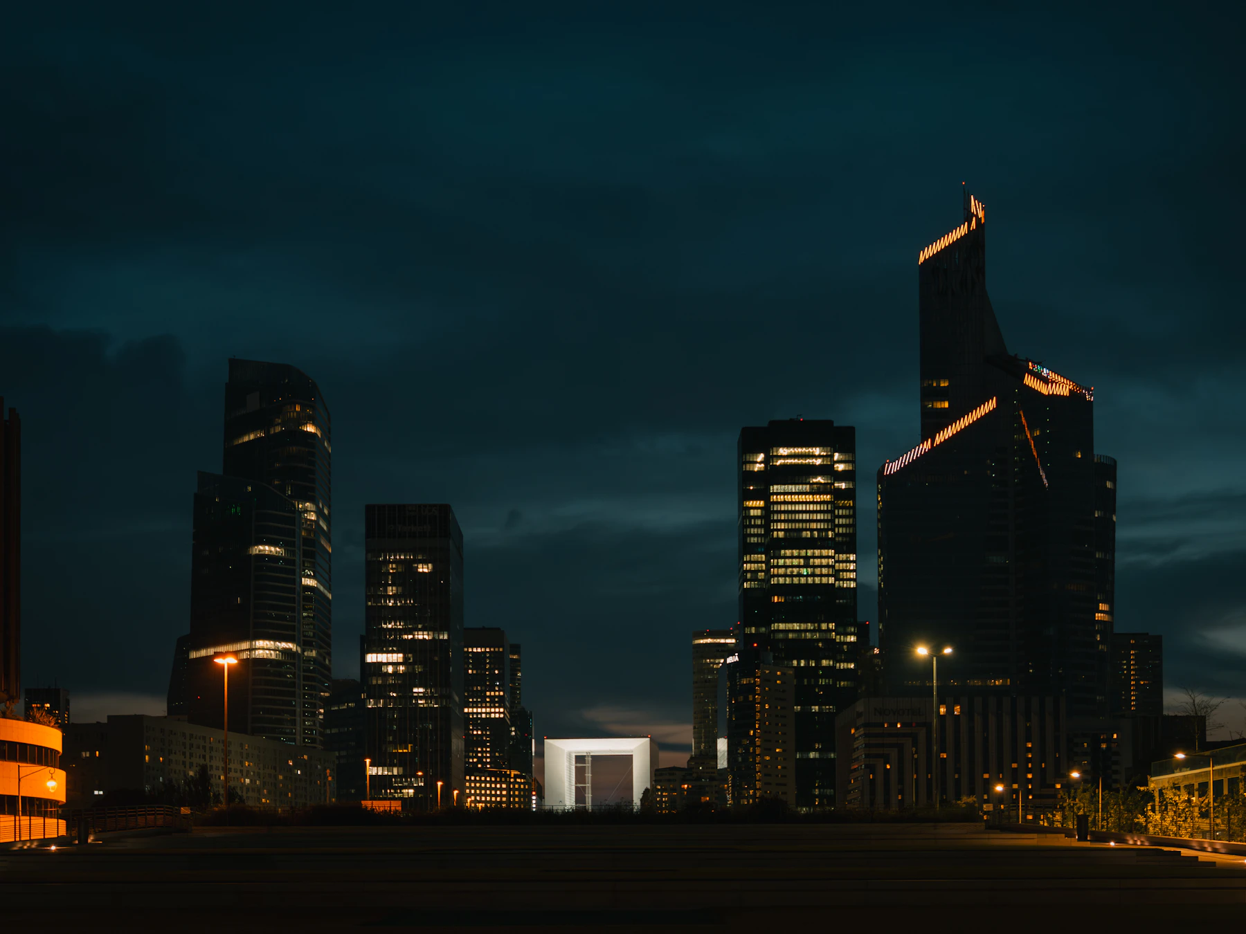 Le quartier d’affaires de La Défense, de nuit, avec la Grande Arche entre les tours